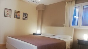 Ein Schlafzimmer mit einem Bett, zwei Nachttischen, einem Fenster mit Vorhängen und drei Bildern an der Wand.