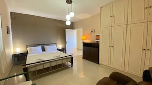 Een slaapkamer met een bed, nachtkastjes, een kledingkast en een bureau met een lamp.