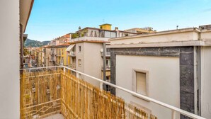 Un balcón con vistas a una hilera de edificios, una valla de bambú y un cielo despejado.