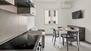 Una cocina moderna con comedor, electrodomésticos integrados y un televisor de pantalla plana.