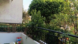 Un balcó amb gespa artificial, una cadira blanca, una petita zona de jocs i una barana de metall negre.