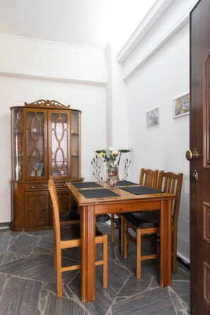 A dining area with a wooden table, chairs, a cabinet, and a vase with flowers. - Maria's Cozy Getaway in Glyfada (Glyfada)