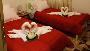 Una habitació d'hotel amb dos llits, cadascun amb roba de llit vermella i tovalloles amb forma de cor.