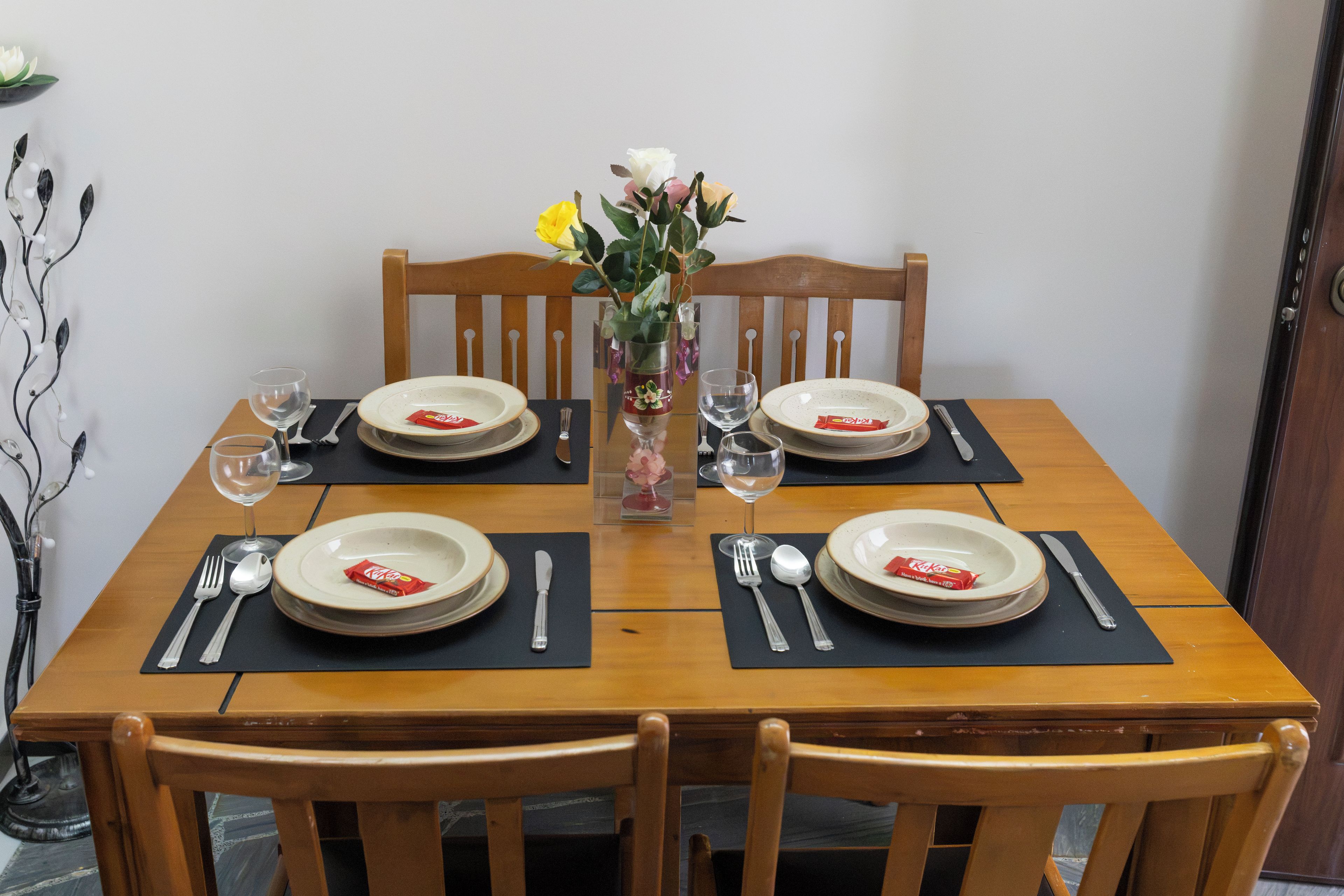 A dining table set for four with plates, cutlery, and glasses.