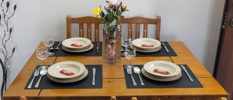 A dining table set for four with plates, cutlery, and glasses.
