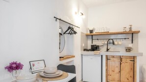 Een praktische keuken met een koelkast, een houten kast en een eethoek met een tafel gedekt voor twee personen.