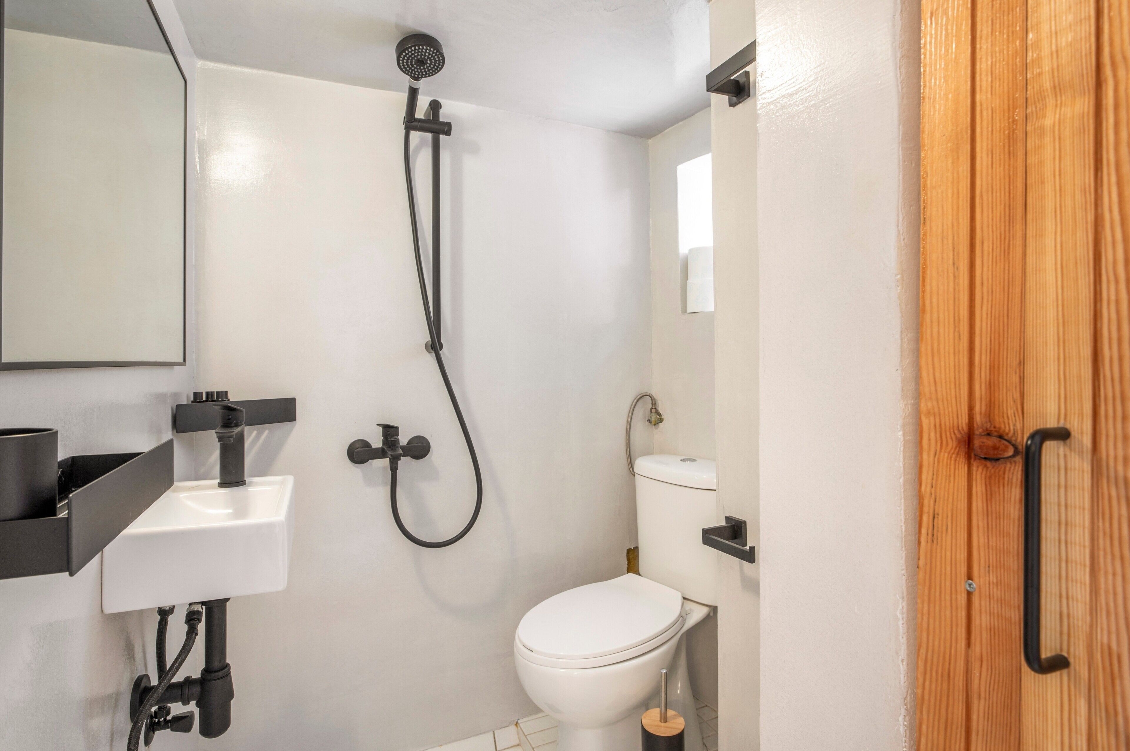 A small bathroom with a white toilet, a sink, and a shower.