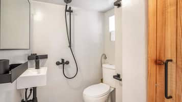 A small bathroom with a white toilet, a sink, and a shower.