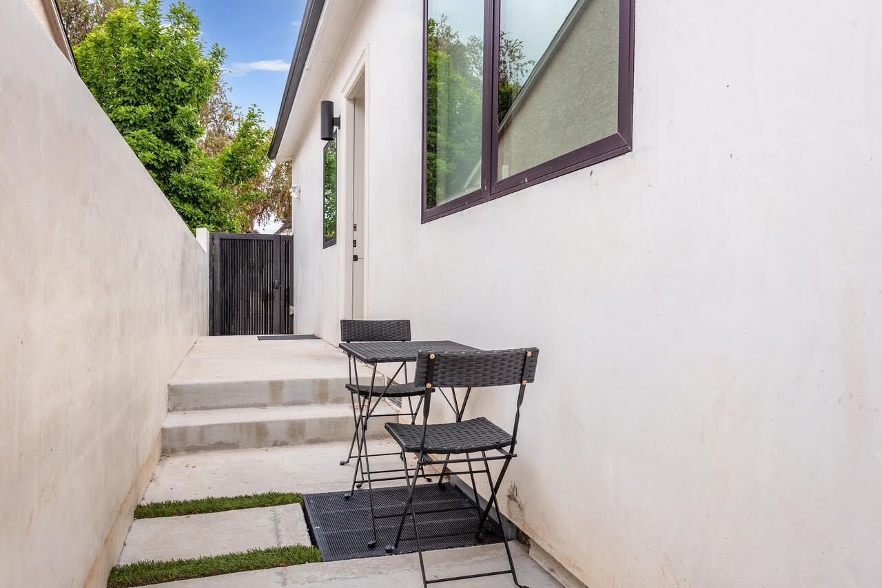 Un petit patio extérieur, avec un escalier en béton, une petite table et deux chaises.