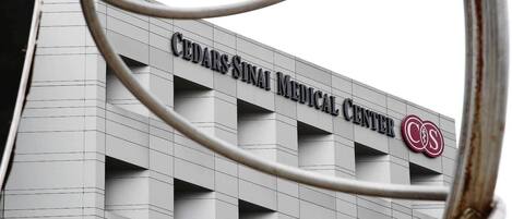 The exterior of Cedar Sinai Medical Center with a modern architectural design and a prominent logo.