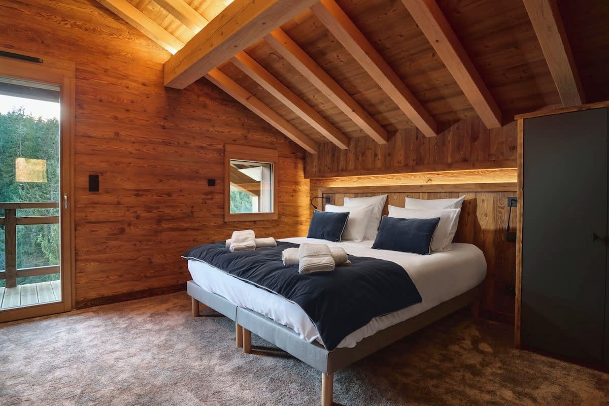 Une chambre dans une cabane en bois, avec un lit, une fenêtre et une porte.