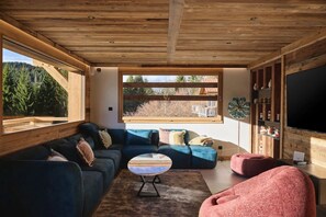 En moderne stue med et stort vindue, en sofa, et sofabord og et fjernsyn.