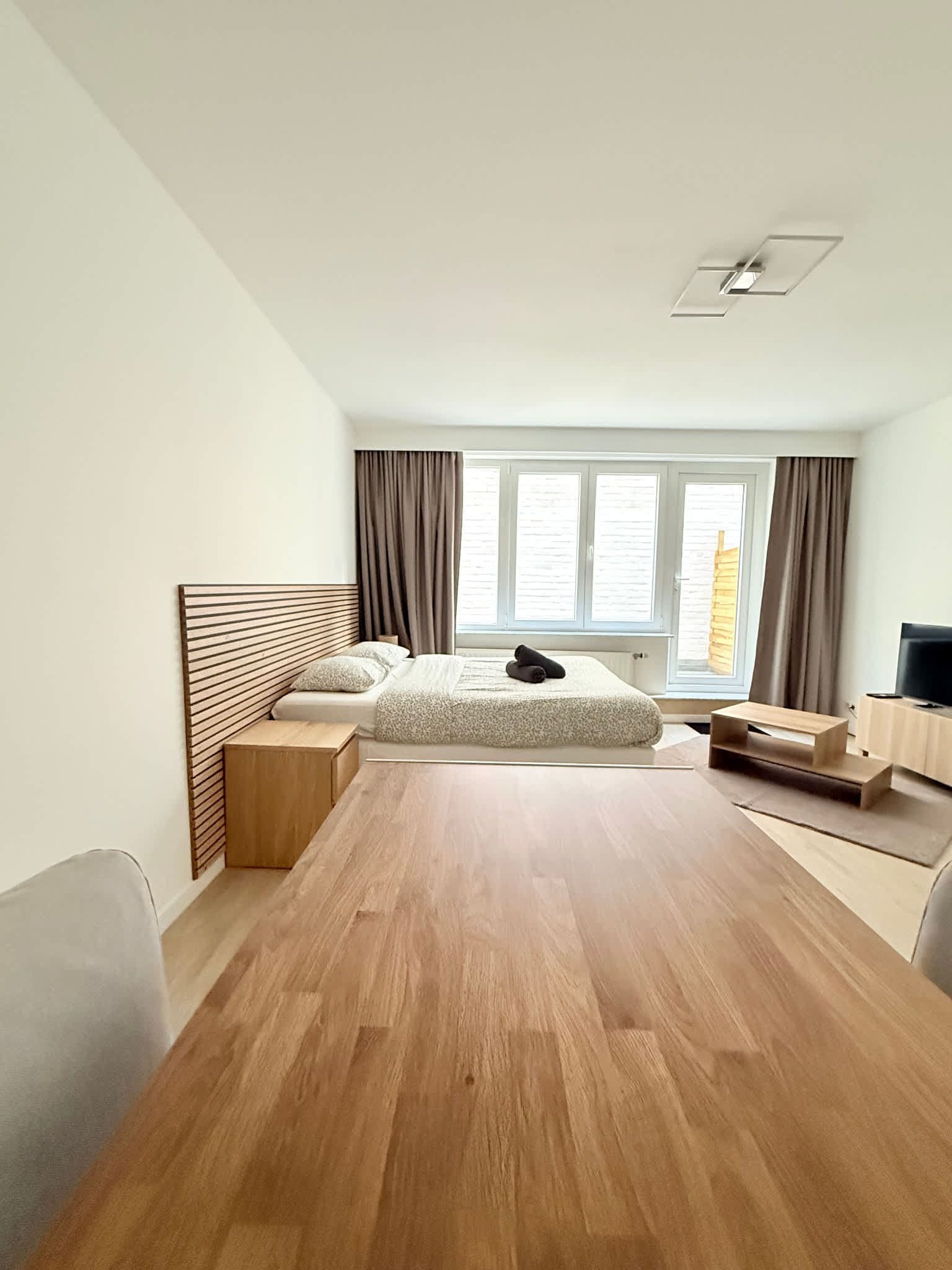 Une chambre à coucher moderne, équipée d’un lit, de tables de chevet, d’un bureau et d’un téléviseur.