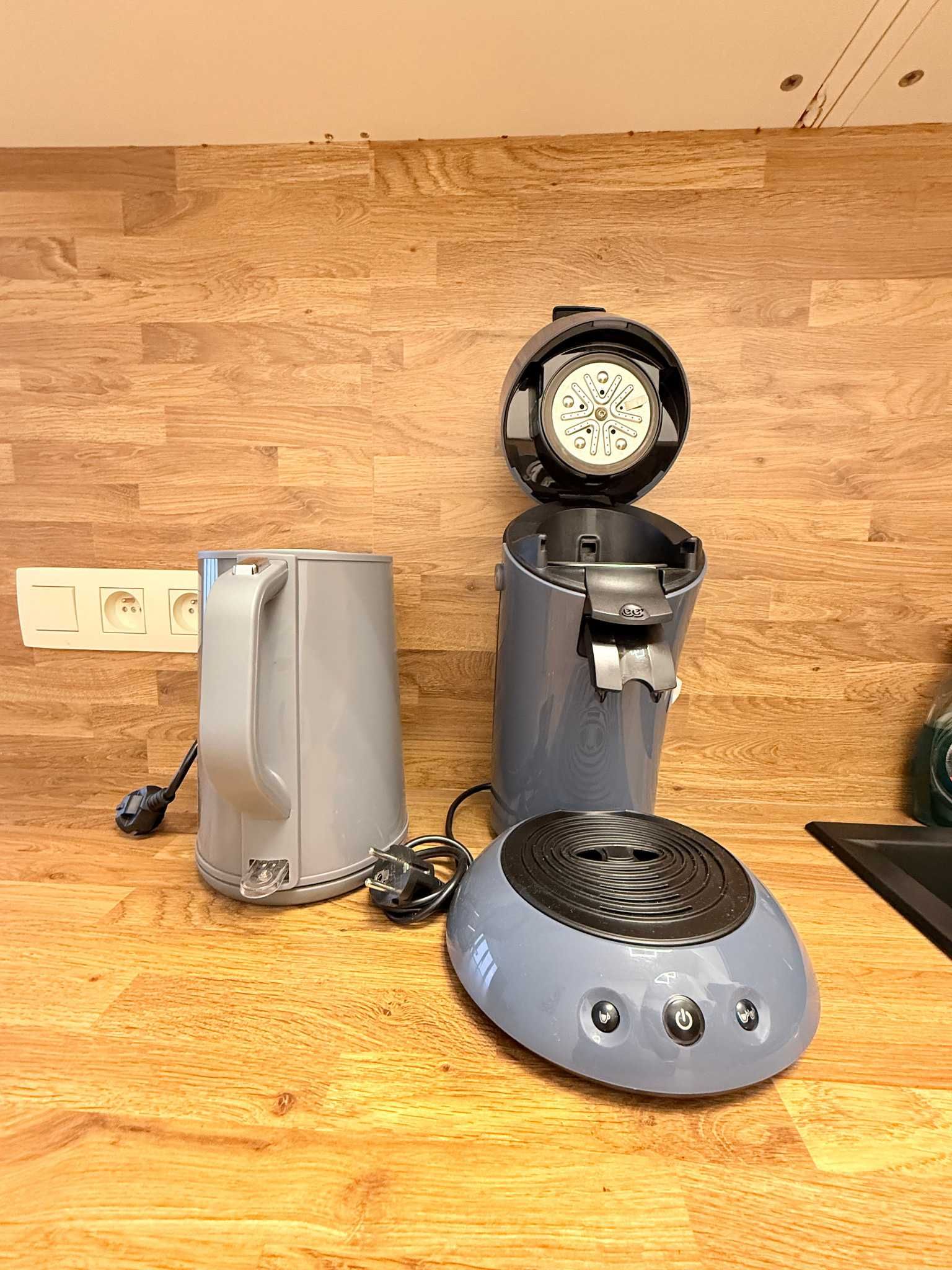 Une cuisine équipée d’une machine à café, d’une bouilloire et d’un four à micro-ondes, le tout posé sur un plan de travail en bois.
