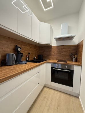 Eine moderne Küche mit weißen Schränken, einer Holz Arbeitsplatte, einem eingebauten Backofen und einer Kaffeemaschine.