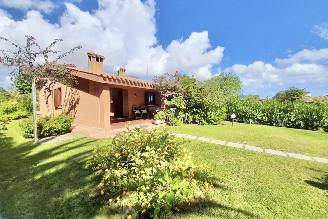 Una casa de un piso con fachada marrón, un pequeño porche y un jardín bien cuidado.