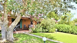 A house with a garden, a patio with chairs, and a tree with purple flowers. - <b></b>Located on the southeastern coast of Sardinia, 20 km from Villasimius, <b>Villa Venere</b> is situated approximately 2 km from the center of Costa Rei. Surrounded by a spacious and well-kept private garden of about 200 sqm, this charming villa is  (Costa Rei)