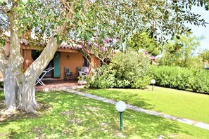 A house with a garden, a patio with chairs, and a tree with purple flowers. - <b></b>Located on the southeastern coast of Sardinia, 20 km from Villasimius, <b>Villa Venere</b> is situated approximately 2 km from the center of Costa Rei. Surrounded by a spacious and well-kept private garden of about 200 sqm, this charming villa is  (Costa Rei)