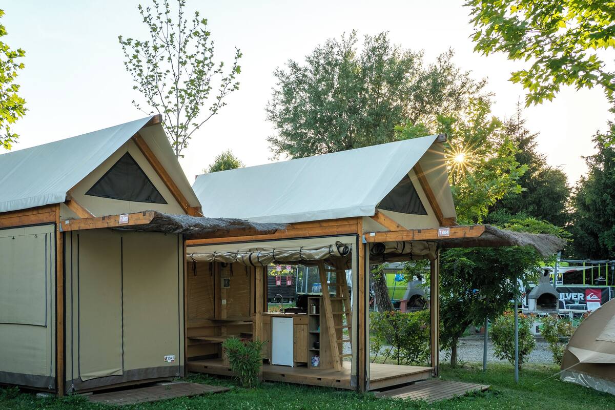 Una pequeña construcción de madera de un solo piso con techo de paja y un espacio al aire libre cubierto.