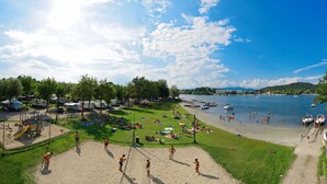 A beach with a volleyball net, tents, and boats in the background. - Lido Verbano Camping Village  (Castelletto Sopra Ticino)