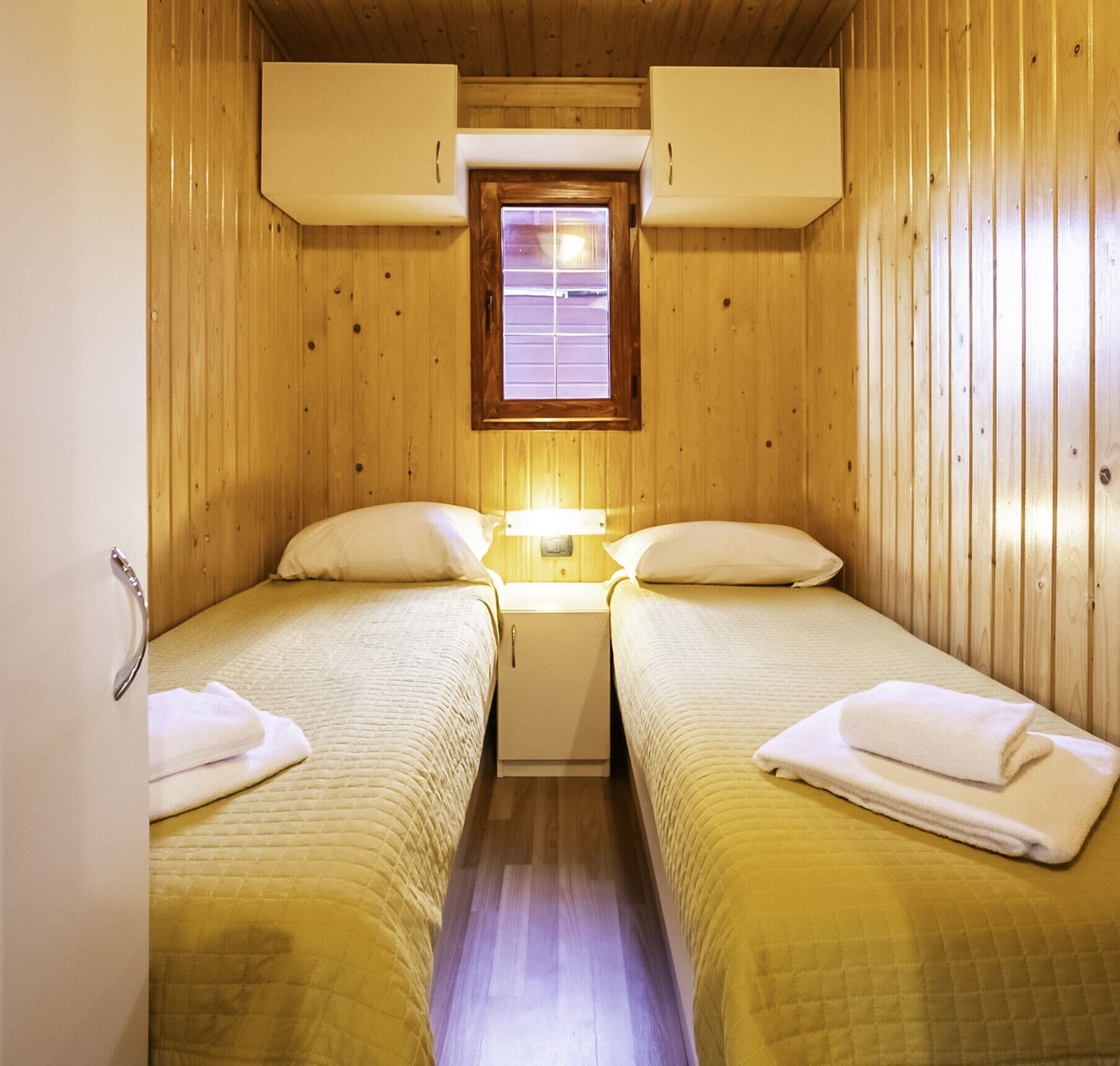 Une petite chambre confortable avec deux lits, une fenêtre et une table de chevet.