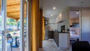 A compact kitchen with modern appliances, a dining area with a table and chairs, and a view of the outdoors through a glass door. - Lido Verbano Camping Village  (Castelletto Sopra Ticino)