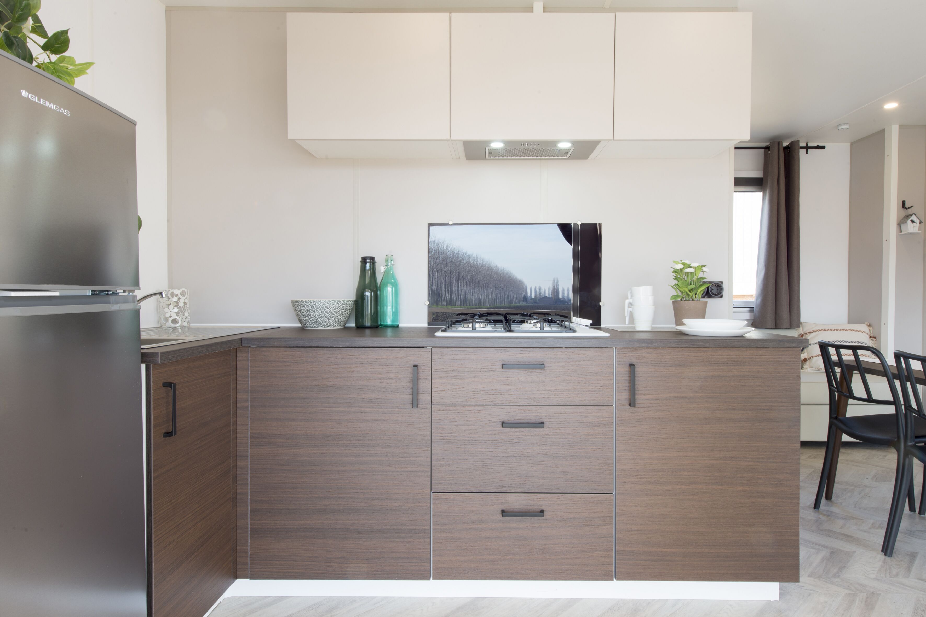 Et moderne køkken med gaskogeplade, køleskab og fladskærms-tv.