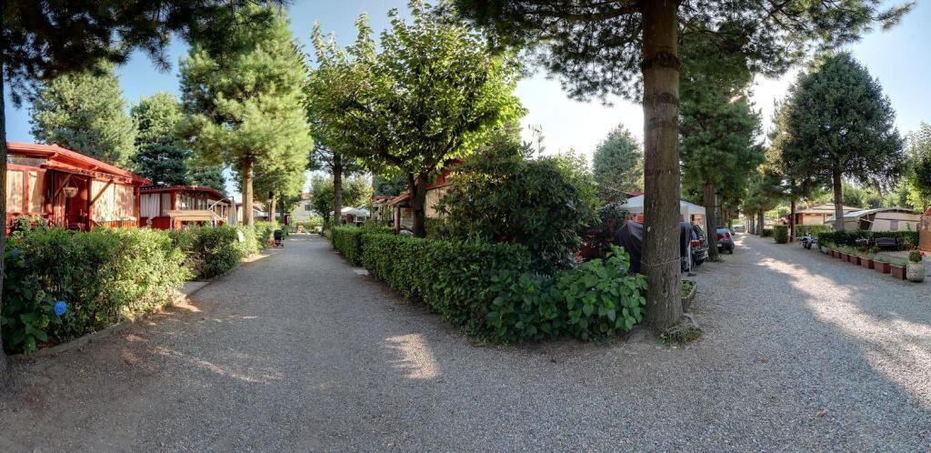 Un sendero de grava bordeado por follaje y construcciones de madera, probablemente parte de un camping o parque.