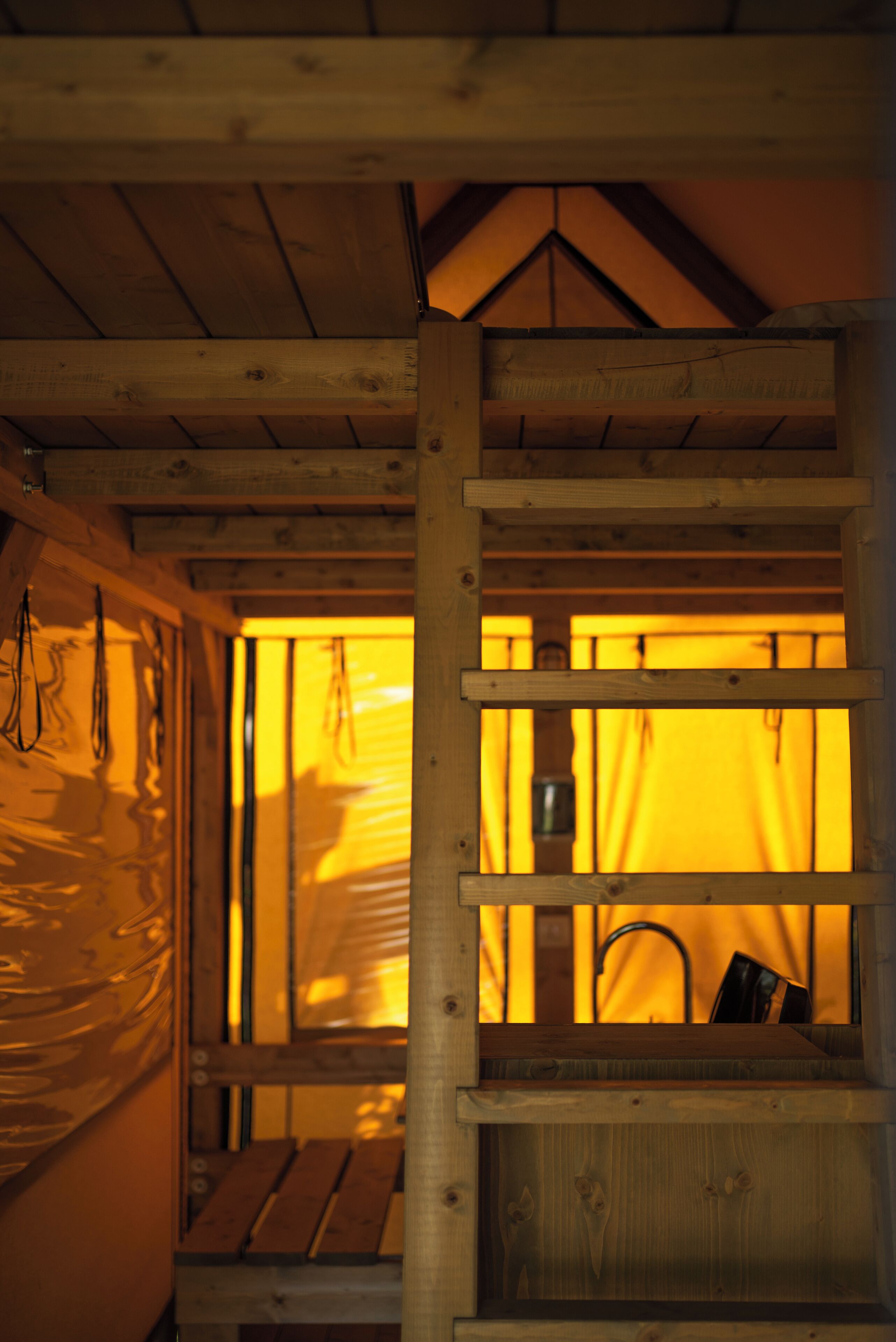 A wooden cabin interior with a window, wooden beams, and a bench.