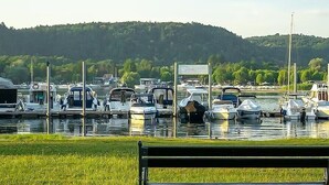 A marina with boats docked, a grassy area, and a bench in the foreground. - Lido Verbano Camping Village  (Castelletto Sopra Ticino)