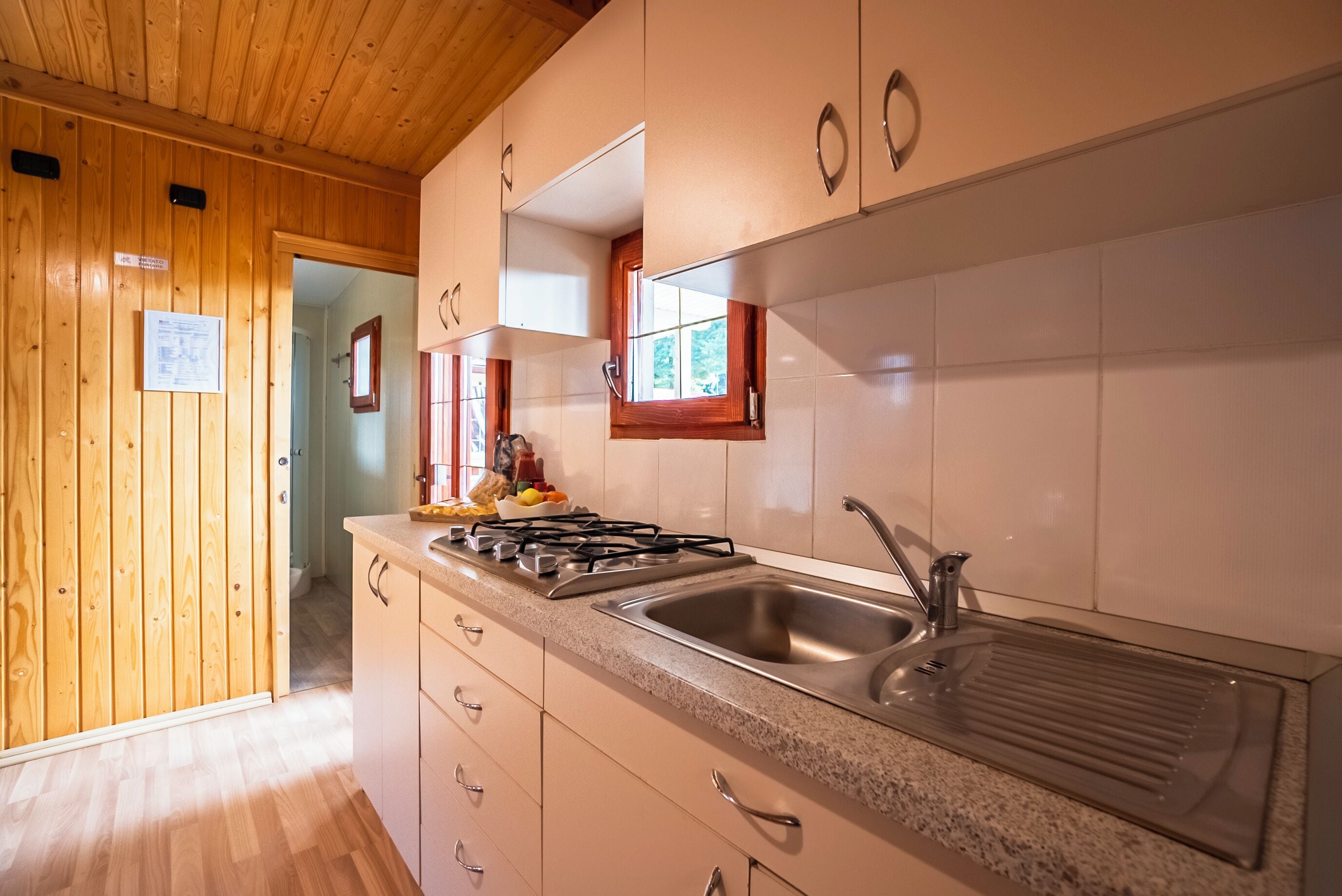A modern kitchen with wooden cabinets, a granite countertop, stainless steel sink, and a gas stove.
