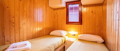 A small, cozy room with wooden walls and two beds.
