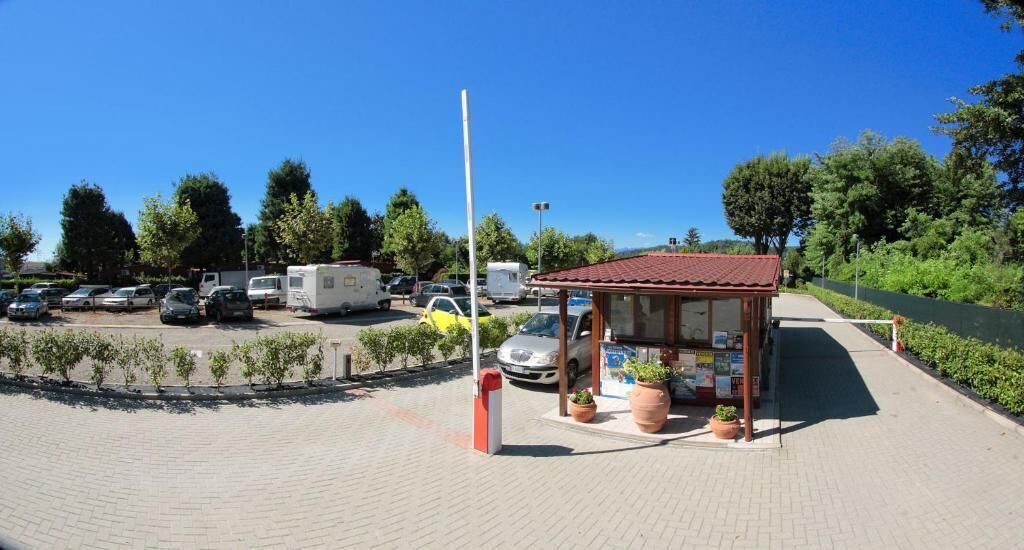 A parking area with RVs and cars, a small kiosk, and a paved walkway.
