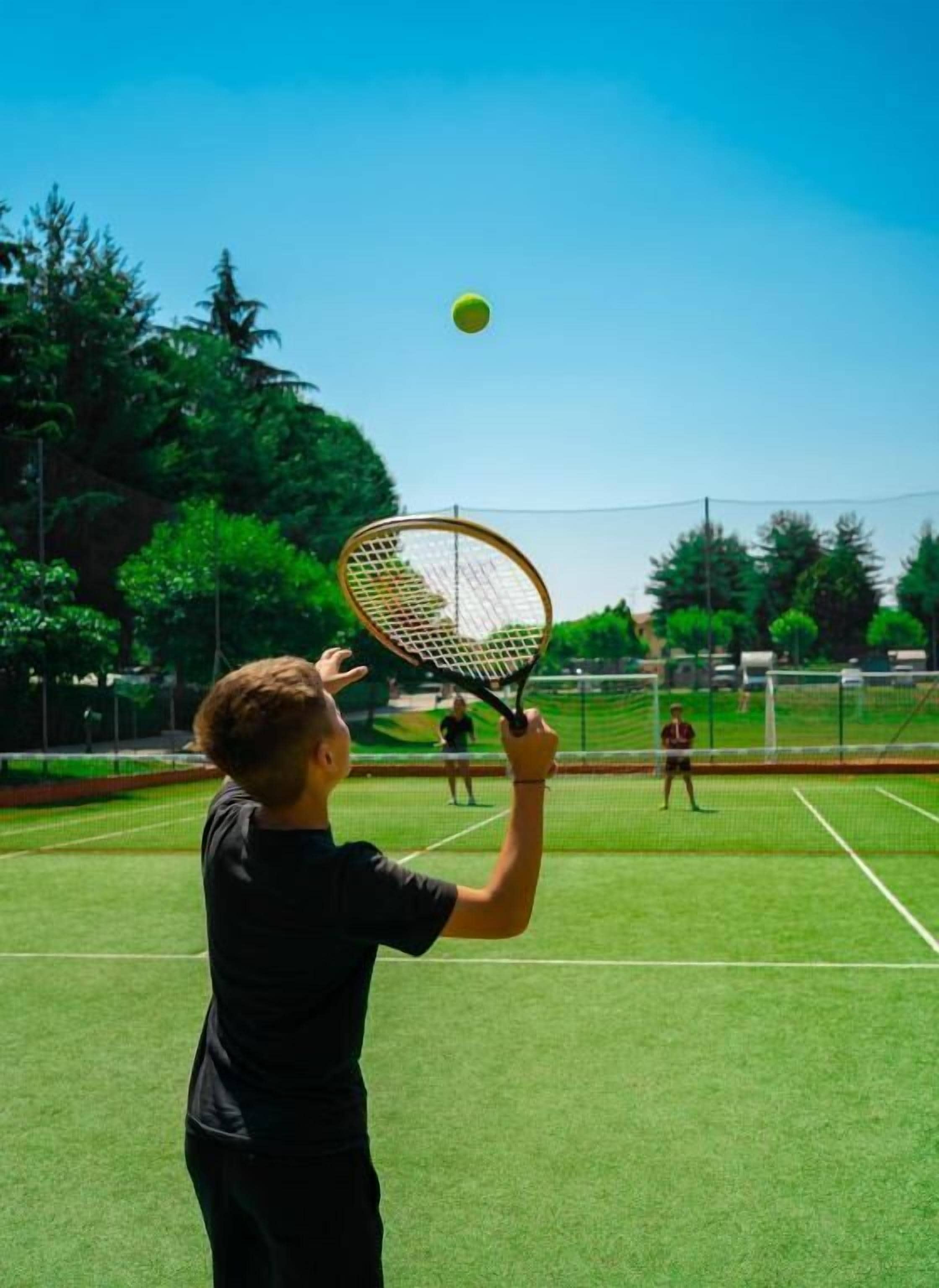 Ein Tennisplatz mit Netz, ein Spieler in Schwarz und ein weiterer Spieler im Hintergrund.