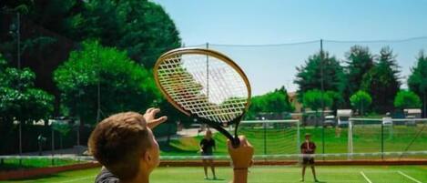 Ein Tennisplatz mit Netz, ein Spieler in Schwarz und ein weiterer Spieler im Hintergrund.