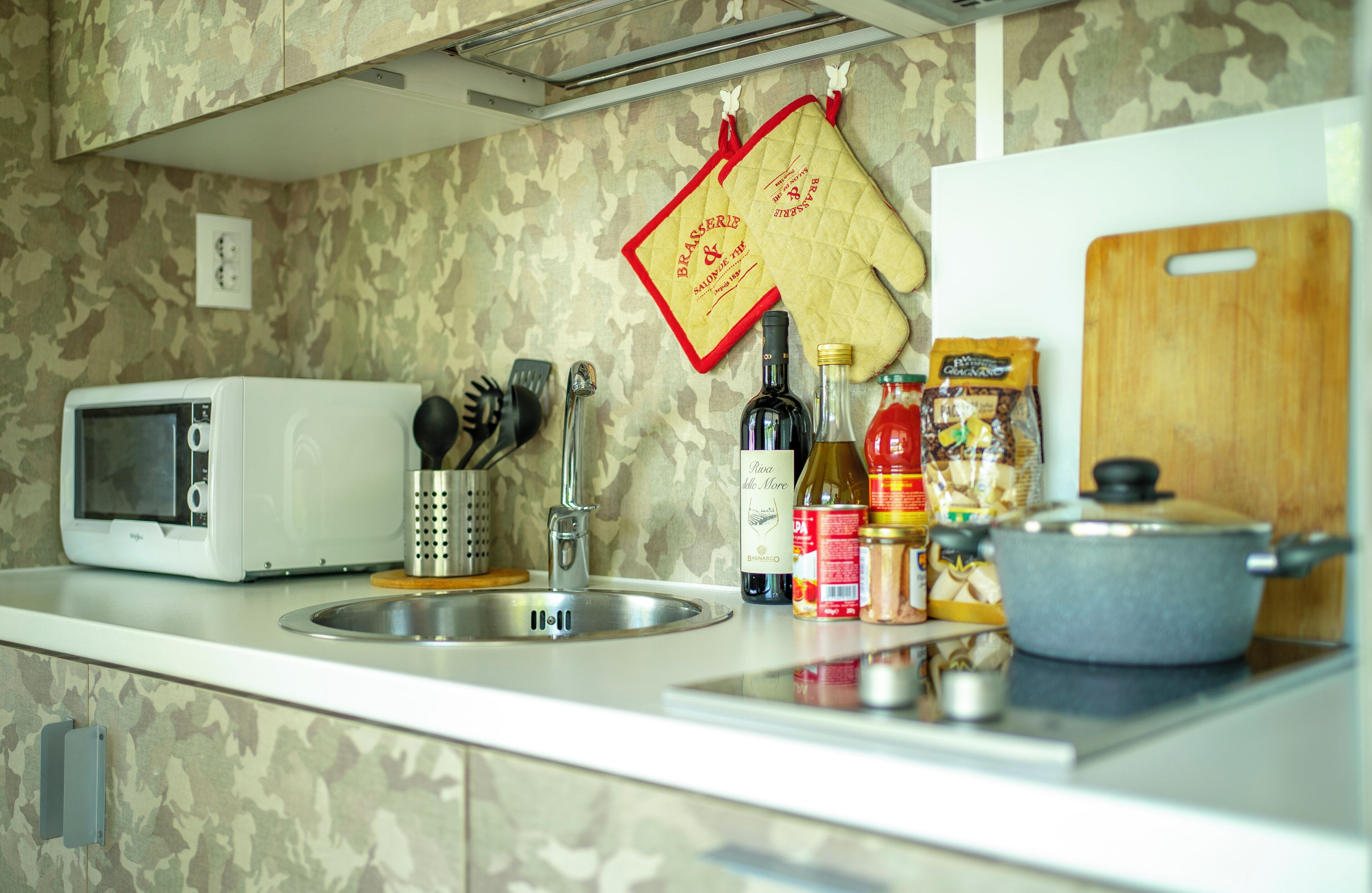 A kitchen with a microwave, sink, and various cooking utensils.
