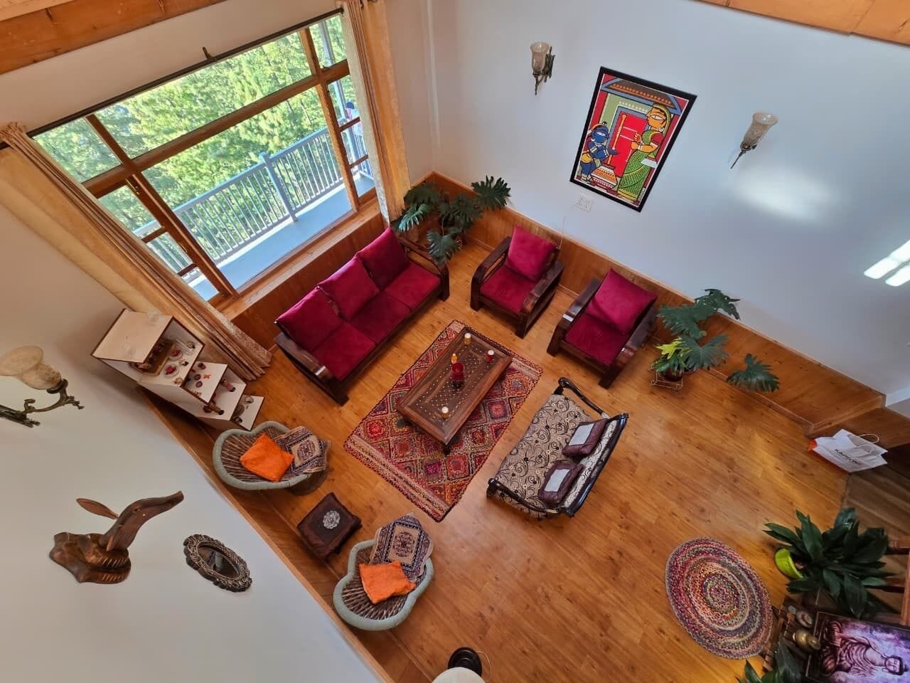 Amplia sala de estar con un gran ventanal, varias zonas de estar y alfombras decorativas.