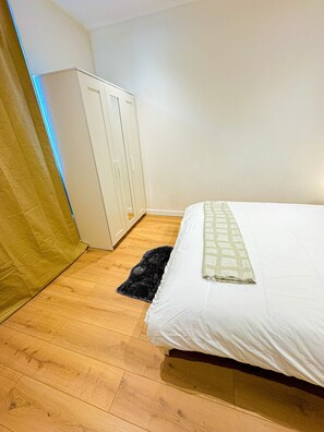 A bedroom with a bed, a wardrobe, and a wooden floor. - 1BR Apt With Living Room Near CityArea (Ghent)