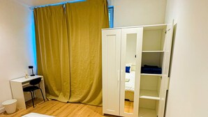 A bedroom with a bed, a desk, and a wardrobe.