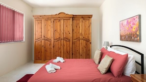 A bedroom with a bed, a wooden wardrobe, a painting, and a window with curtains. - Spacious & Cosy APT - Msida Uni Heights (Msida)