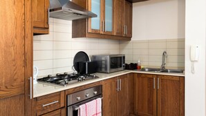 A kitchen with wooden cabinets, a stove, a microwave, and a sink. - Spacious & Cosy APT - Msida Uni Heights (Msida)