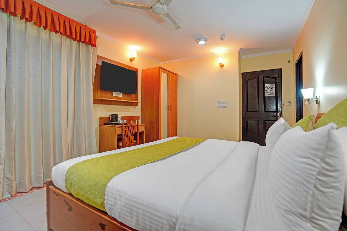 Une chambre d’hôtel équipée d’un lit, d’un bureau, d’une chaise, d’une télévision et d’une porte avec une pancarte.