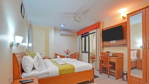 Une chambre d’hôtel comprenant un lit, une table de chevet, un bureau, une chaise, une télévision et une armoire.