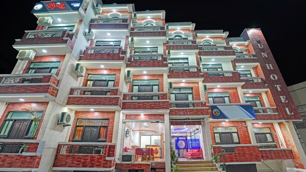 Un hôtel à plusieurs étages, doté de balcons, de climatiseurs et d’une enseigne indiquant « Sun Hotel ».