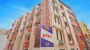 Un immeuble à plusieurs étages, sur lequel on peut voir une grande enseigne indiquant « Sun Hotel » et une banderole annonçant « The Byke Boutique Hotel ».