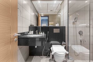Ein modernes Badezimmer mit einem schwarzen Waschtisch, einer Toilette und einer durch eine Glaswand abgetrennten Duschkabine.