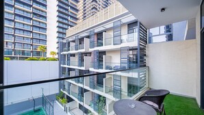 Apartamento moderno com varanda, quadra de tênis e área de jantar com cadeiras.