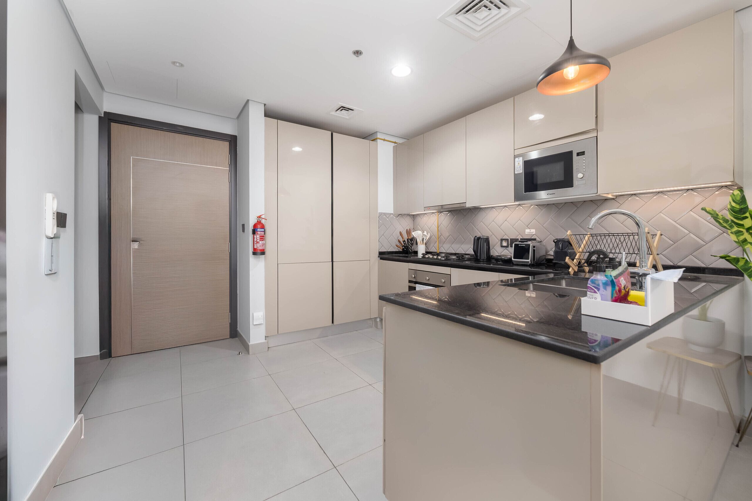 A modern kitchen with a central island, stainless steel appliances, and a pendant light.