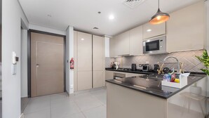 Uma cozinha moderna com uma ilha central, eletrodomésticos de aço inoxidável e uma luminária pendente.