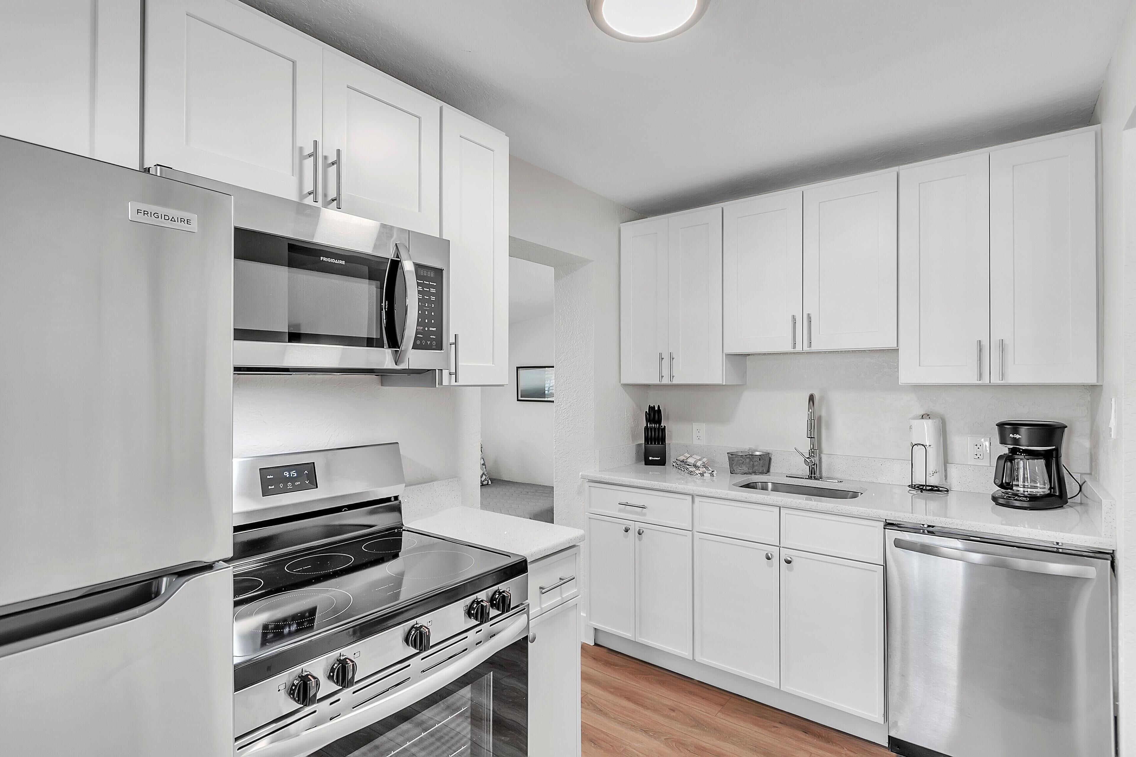 A modern kitchen with stainless steel appliances, white cabinetry, and a dishwasher.